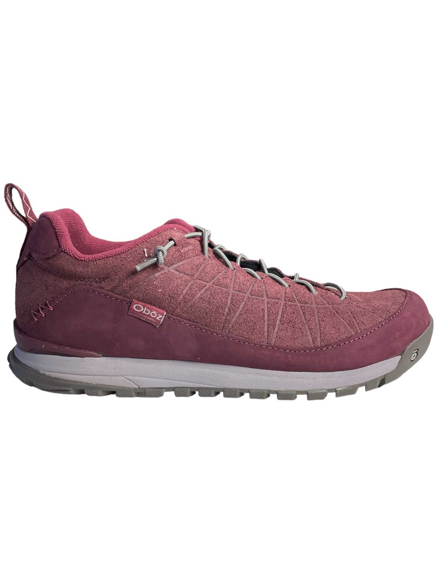 A side view of the Oboz Womens Jeannette Low Shoe in pink, featuring a textured upper made from recycled fibers, gray sole, lace-up closure, small Oboz tag near the heel, and a back pull loop.