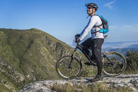 a man with a white long-sleeved jersey riding a bicycle on a mountain