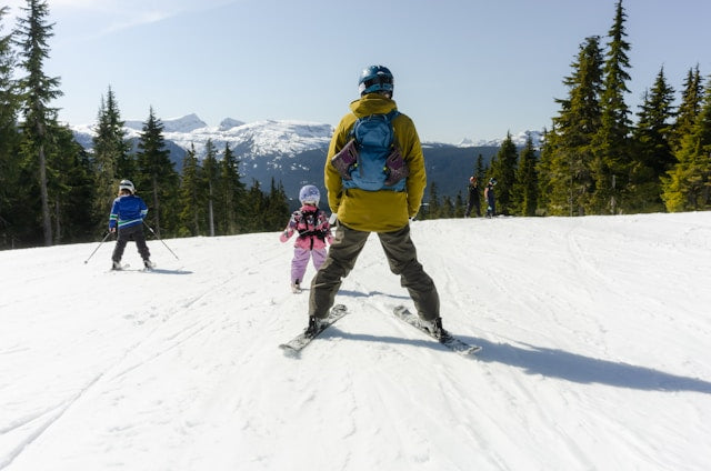 A parent skiing with two children