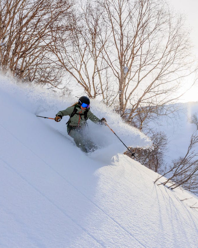 Person skiing down a snowy slope with trees in the background
