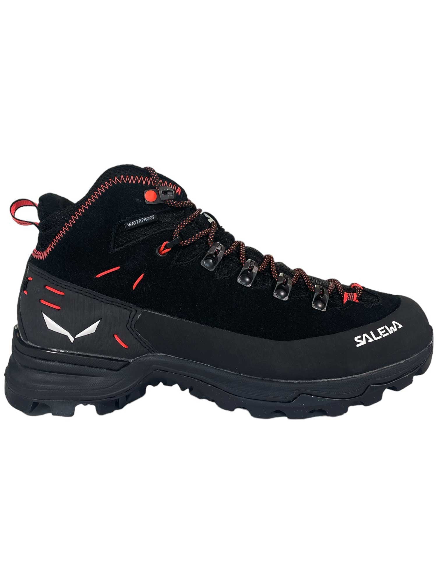 The Salewa Womens Alp Mate Winter Mid Waterproof Boot is a black hiking boot with red accents, rugged sole, red-and-black laces, and white Salewa logos on the side and heel. Sturdy winter mid boots made for outdoor adventures.