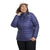 A smiling woman in The North Face Womens Plus ThermoBall Eco 2.0 Jacket, a white cap, and black pants stands with one hand on her collar against a plain white background.