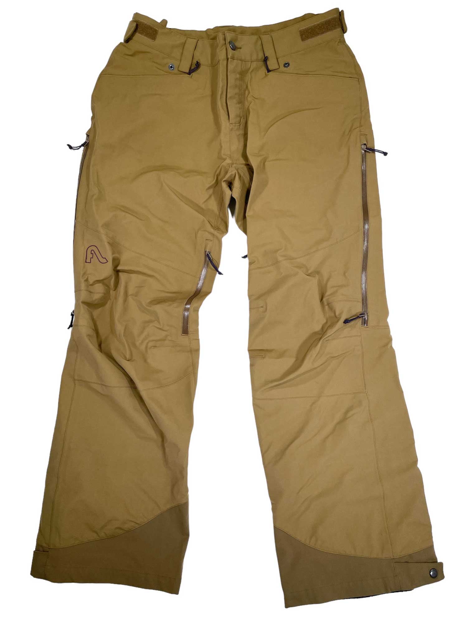 Women’s Donna Pants in light brown feature zippered pockets, adjustable waist tabs, and reinforced ankle fabric for breathable comfort. The ski pants are shown laid flat on a white background.