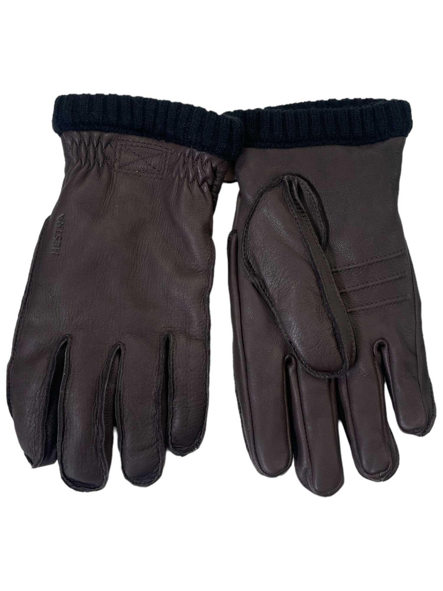 The Hestra Men's Deerskin Primaloft Ribbed Glove features dark brown deerskin leather and black ribbed knit cuffs—ideal for outdoor activities, combining style and durability. Shown side by side on a white background.