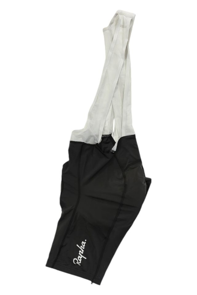 Mens Bib Shorts: Black cycling bib shorts with white mesh shoulder straps and "Rapha" in white script on the left leg, showcased on a white background.