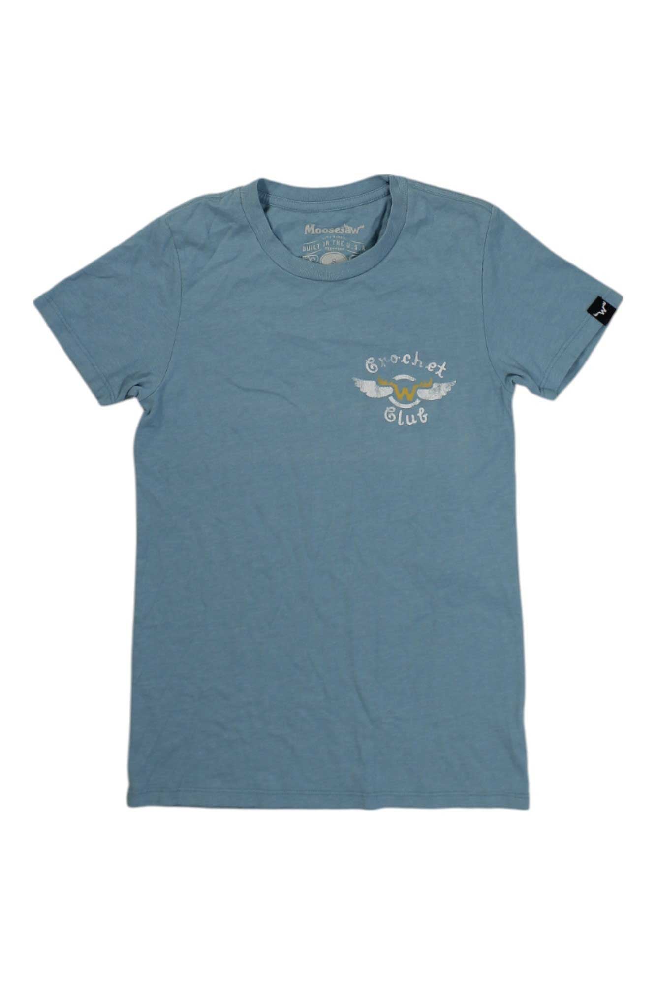 The Moosejaw Women's Monte Cristo SS Tee is a light blue vintage short sleeve crew with a small white and yellow Crochet Club logo with wings on the left chest and a black tag on the left sleeve. Made in USA.