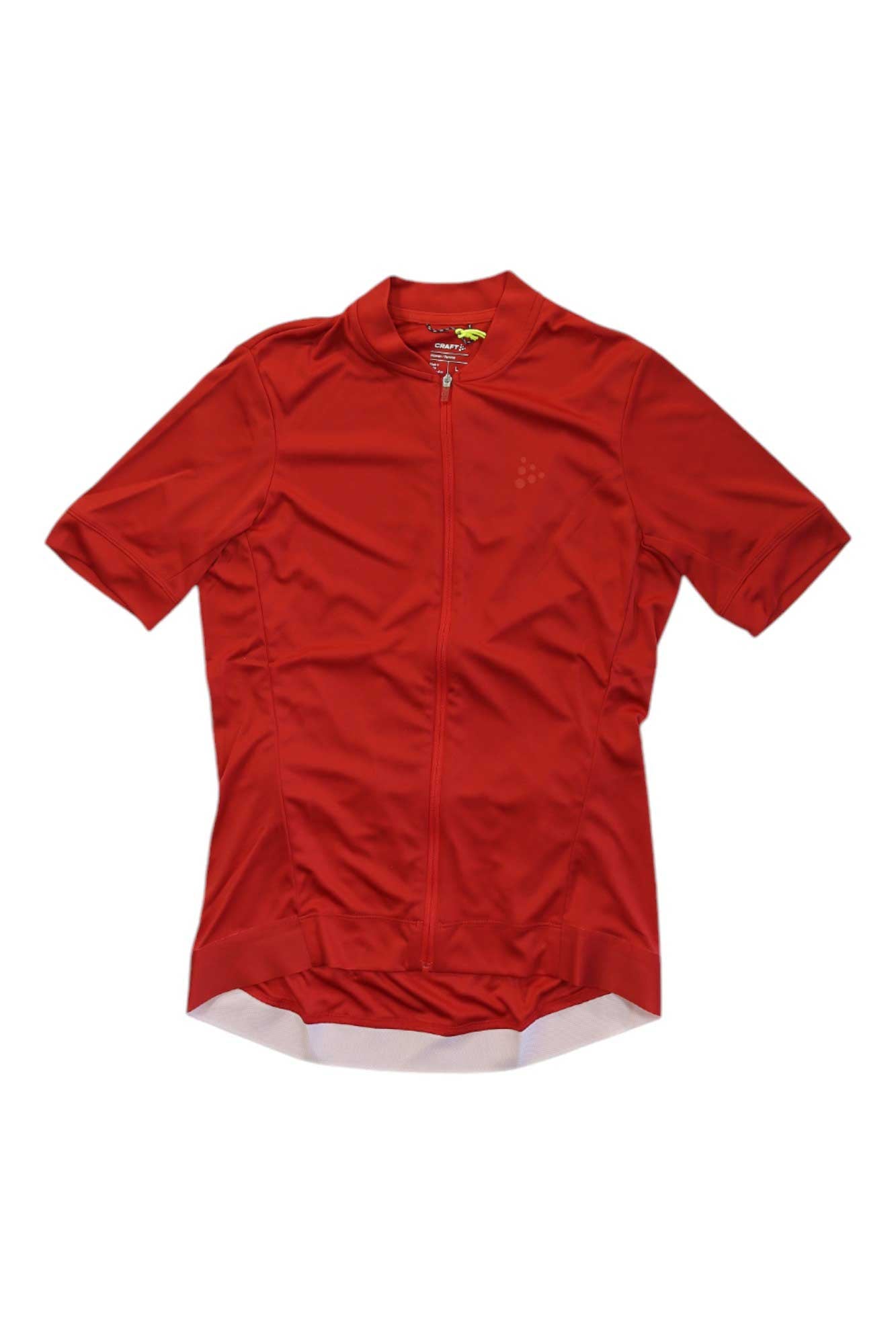 The Craft Sportswear Womens Essence Jersey is a short-sleeved, bright red cycling top for women, made of moisture-wicking fabric with a full front zipper and extended back hem, shown laid flat on a white background.