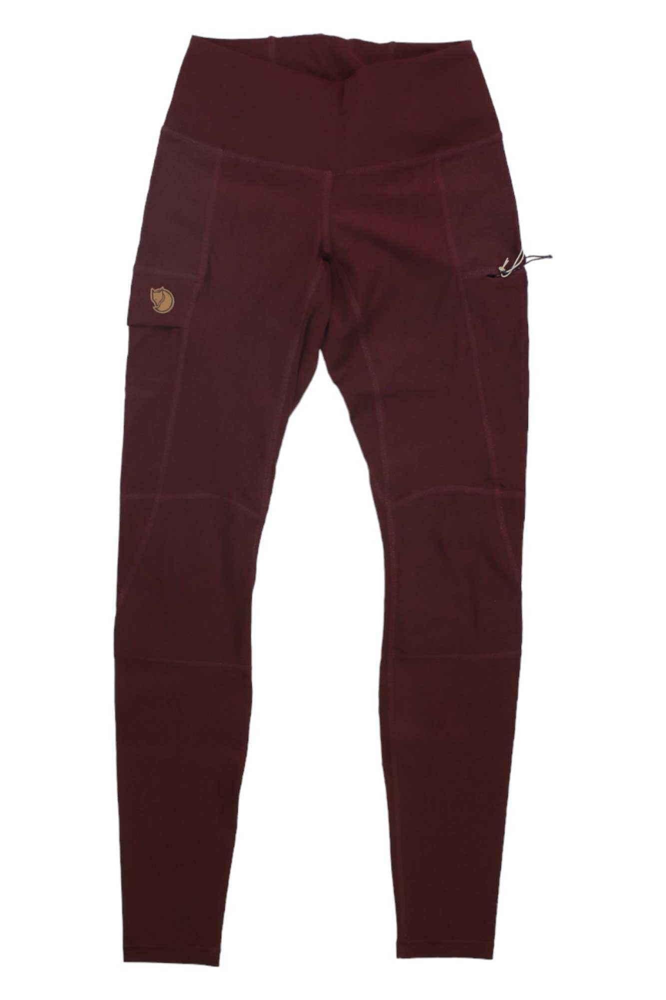 The Abisko Trail Tights are high-waisted burgundy leggings with a small logo patch on the right pocket, drawstring loop on the left, four-way stretch, slim fit, and stitched panel design.