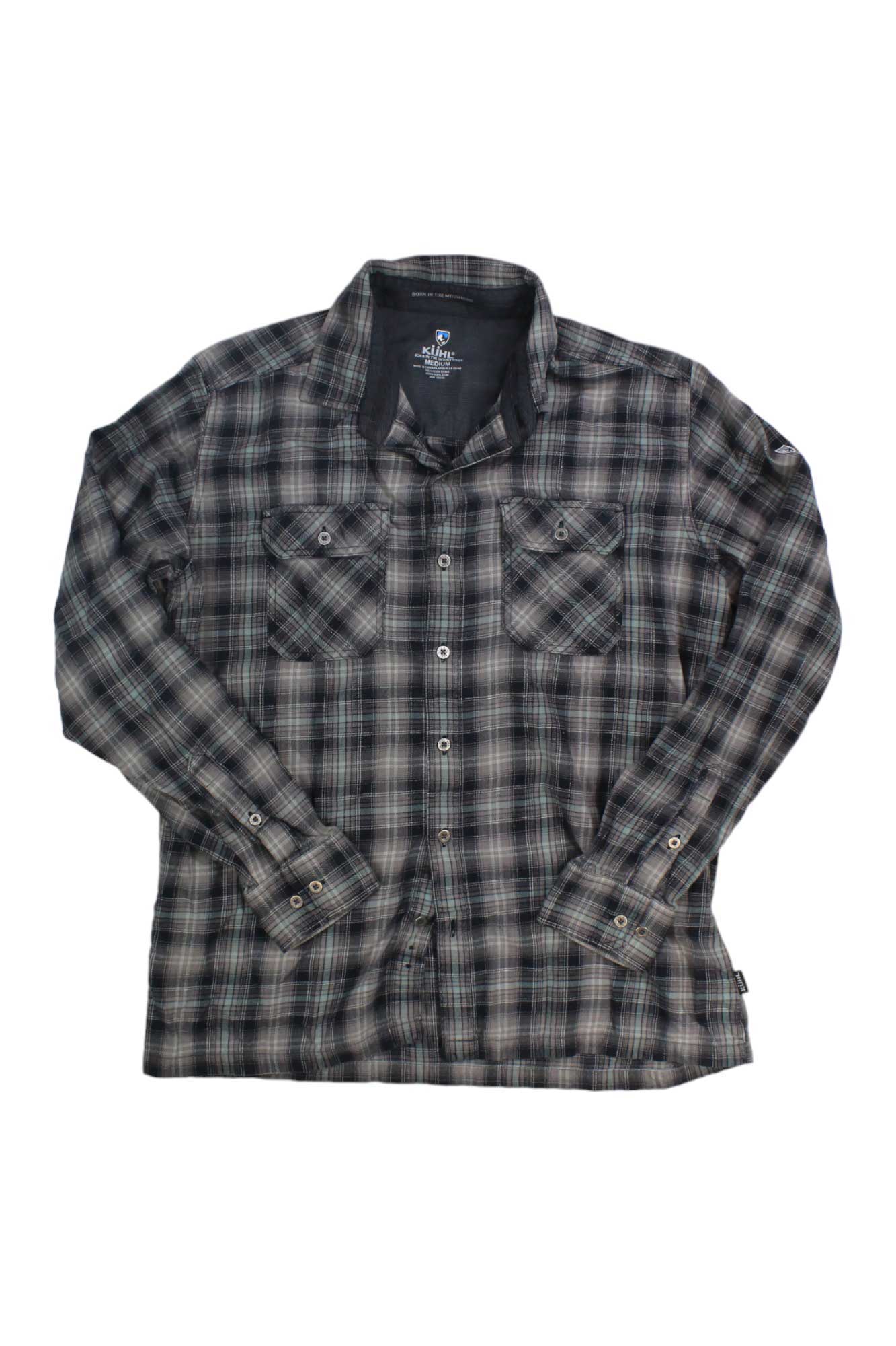 The Kuhl Mens Dillingr Flannel Shirt is a long-sleeve, button-up men’s shirt in black, gray, and white plaid with two chest pockets, shown laid flat on a white background.