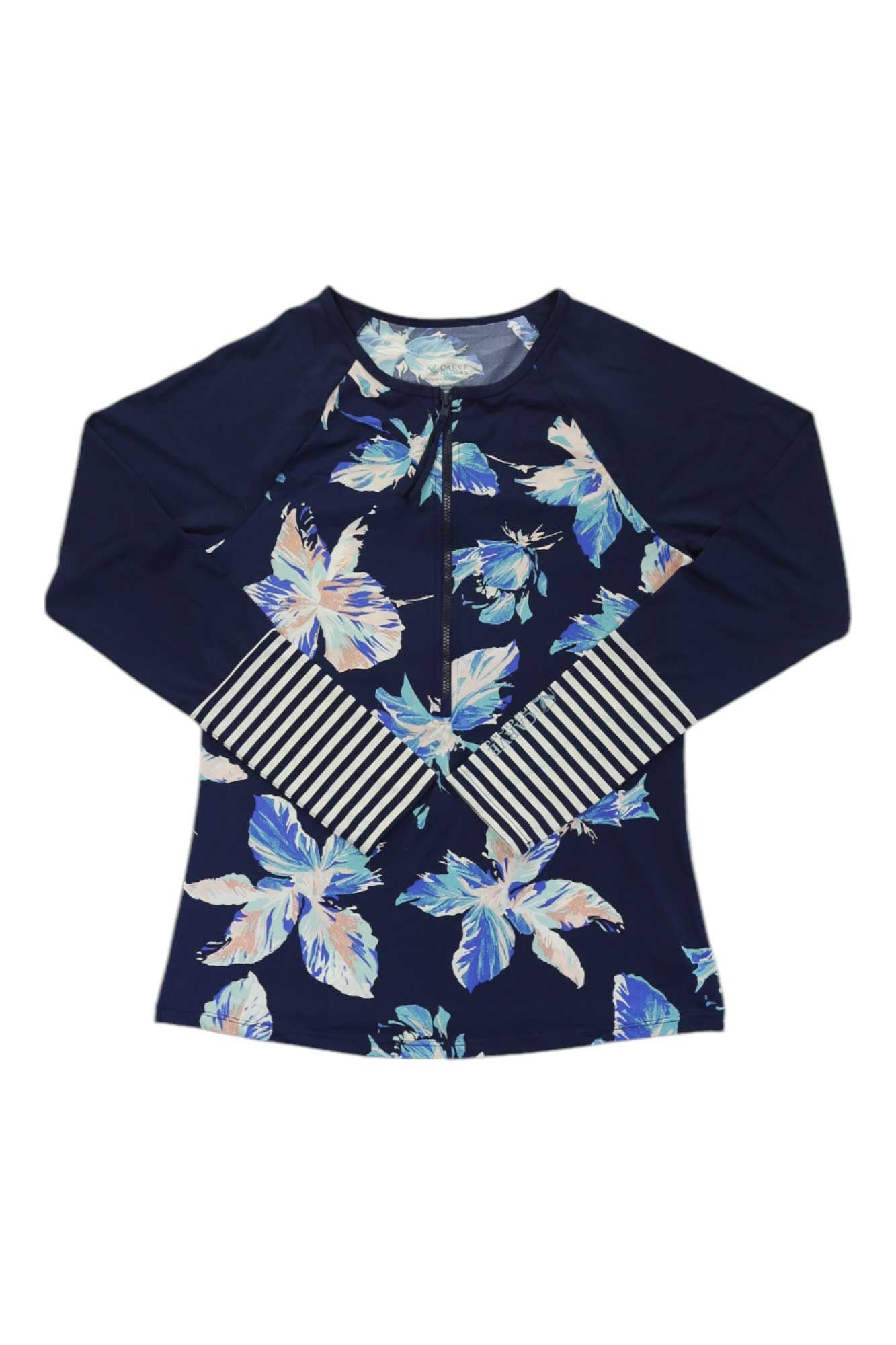 The Carve Designs Womens Kona Rashguard is a navy blue, long-sleeved rashguard with a light blue and white floral pattern, black-and-white striped cuffs, front zipper, raglan sleeves, and sun protection for comfort.