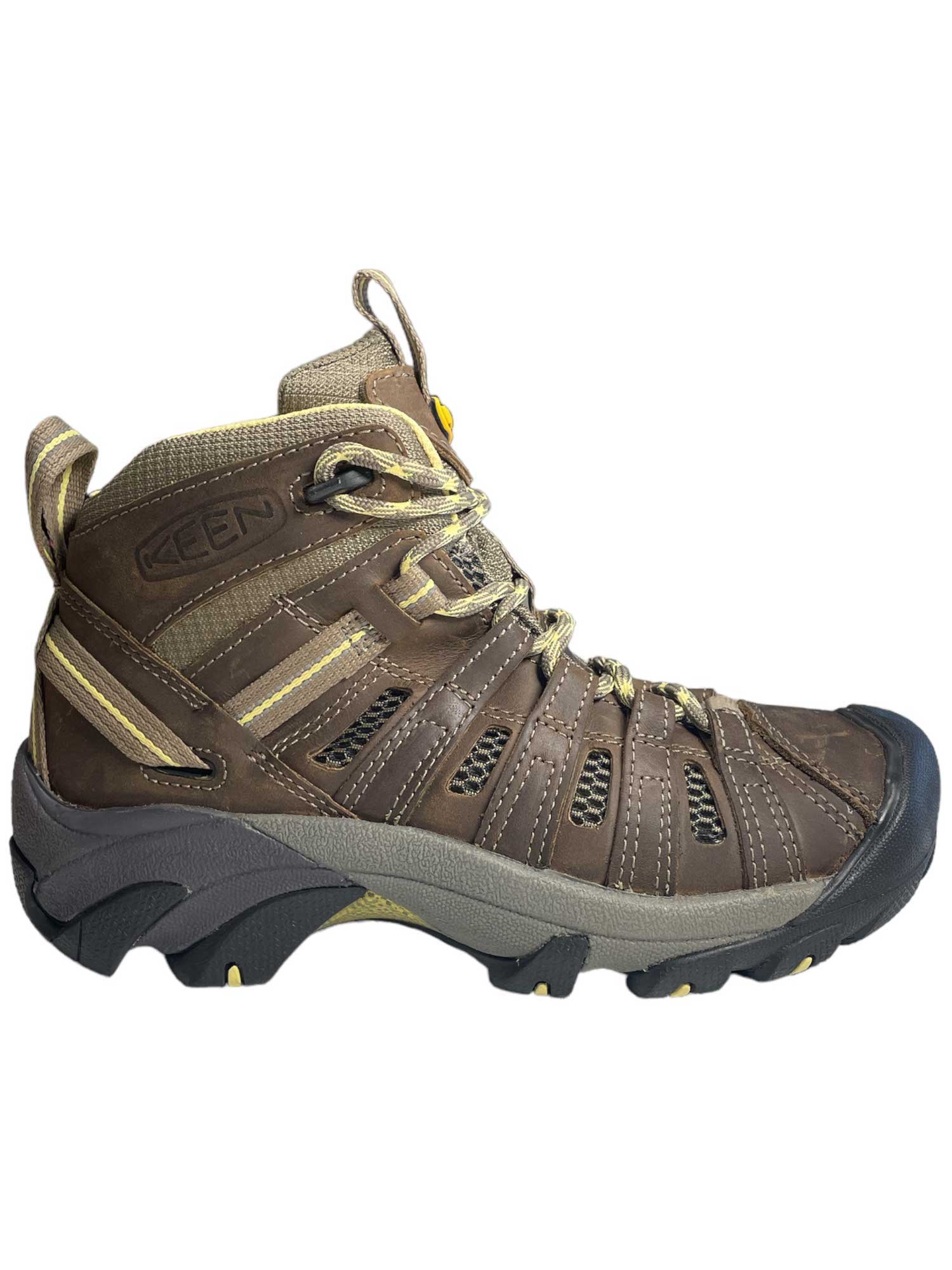 The KEEN Women's Voyageur Mid Boot, shown from the side on a white background, features brown and tan colors, a reinforced toe, rugged sole, lace-up front, and breathable mesh upper.