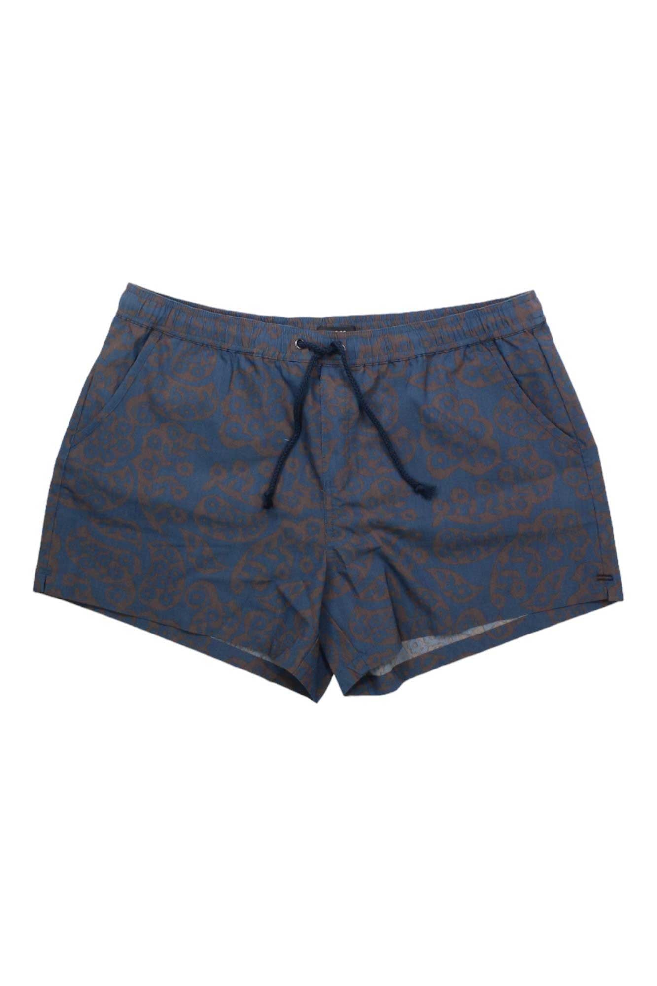 The Toad & Co Women's Boundless 4 Inch Short features a brown abstract pattern on blue, an elastic waistband with drawstring, moisture-wicking comfort, and a short length. Shown laid flat on a white background.