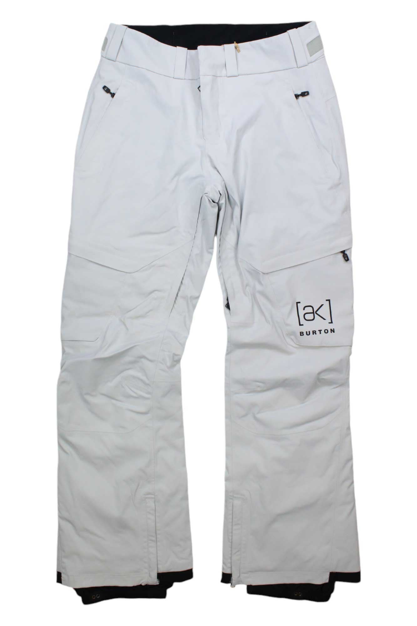 The Burton Womens [ak] GTX Summit Insulated Pant is a pair of white snow pants with zippered pockets, belt loops, reinforced cuffs, and the [ak] BURTON logo on the left thigh. They feature a relaxed fit for winter sports.
