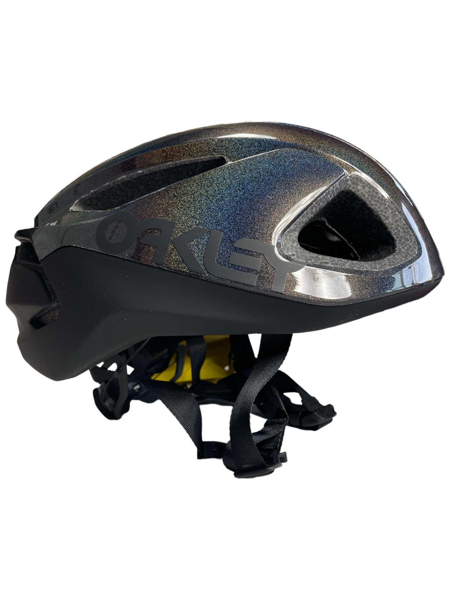 The Oakley Mens ARO3 Helmet, shown in black with iridescent details, features ventilation holes, adjustable straps, MIPS protection, and is designed for seamless eyewear integration.
