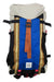 The Topo Designs Mountain 16L Pack is a hiking backpack with a beige top flap, blue front panel, brown and orange straps, black sides, side pockets, a white logo tag near the bottom, and an interior laptop sleeve.