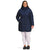 A woman stands facing forward, smiling with her hands in the pockets of a long, navy The North Face Women's Plus Metropolis Parka over white leggings and black slip-on shoes, set against a plain white background.