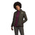 A woman with curly hair wears an olive green The North Face Womens Shady Glade Insulated Jacket over a burgundy turtleneck and dark pants, standing against a plain white background. The North Face logo is visible on her jacket.