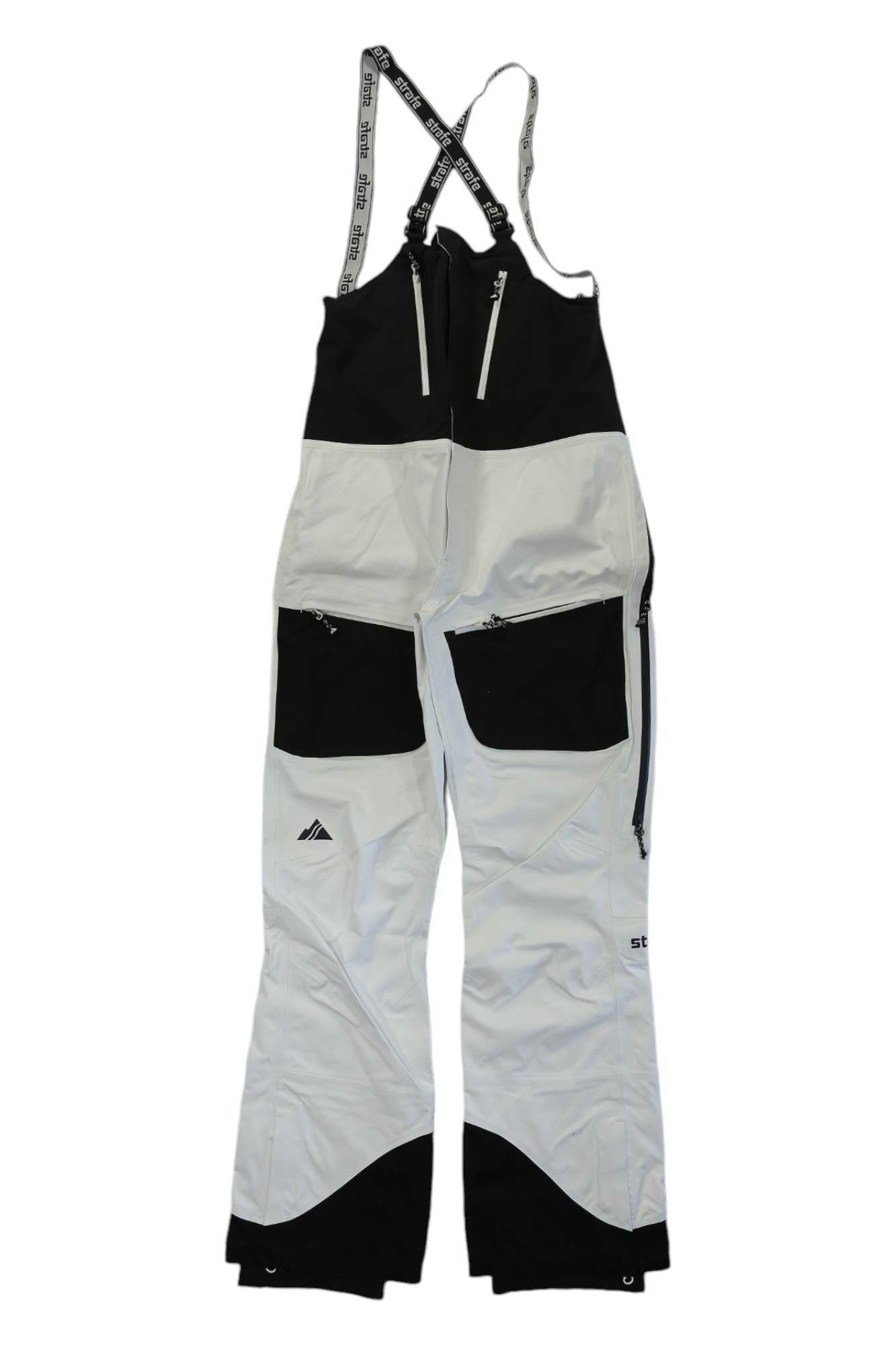 The Strafe Womens Scarlett Bib in white and black features eVent DV Alpine waterproof fabric, adjustable shoulder straps, zippered pockets, reinforced knees and ankles, and a mountain logo on the left leg. Shown on a plain white background.