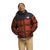 A person smiles with hands in pockets, wearing The North Face Men's 1996 Retro Nuptse Jacket in shiny red and black with 700-fill down insulation, beige pants, and a cream shirt, standing against a plain white background.