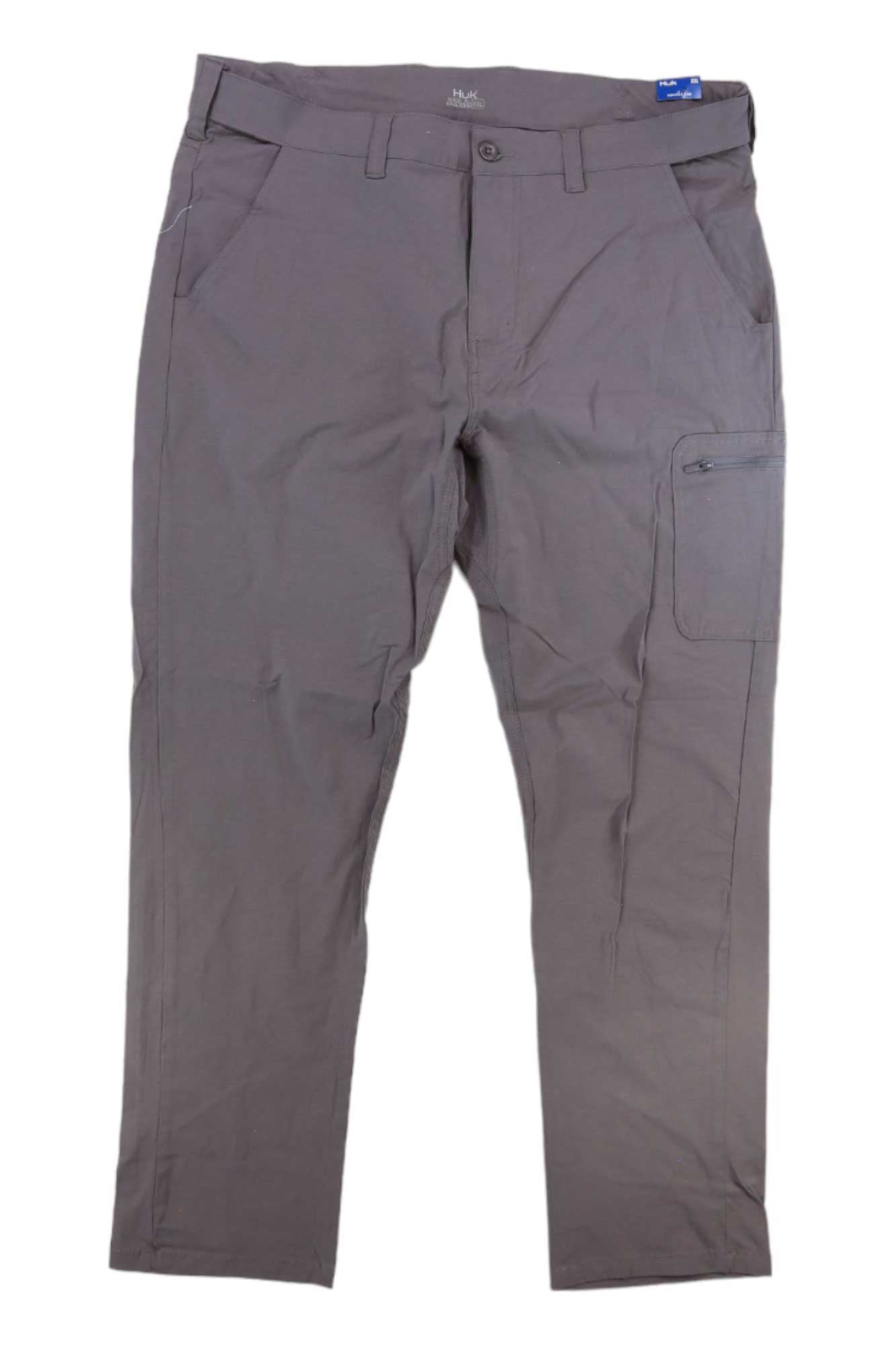 The Huk Mens NXTLVL Pant is a gray outdoor performance pant featuring belt loops, front button and zipper closure, two side pockets, and a right thigh zippered pocket. These quick-drying athletic pants are shown laid flat on a white background.