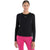 A woman with brown hair tied back is smiling and wearing the Icebreaker Womens Merino 200 ZoneKnit Energy Wind LS Tee in black with white text, paired with bright pink pants, standing against a plain white background.