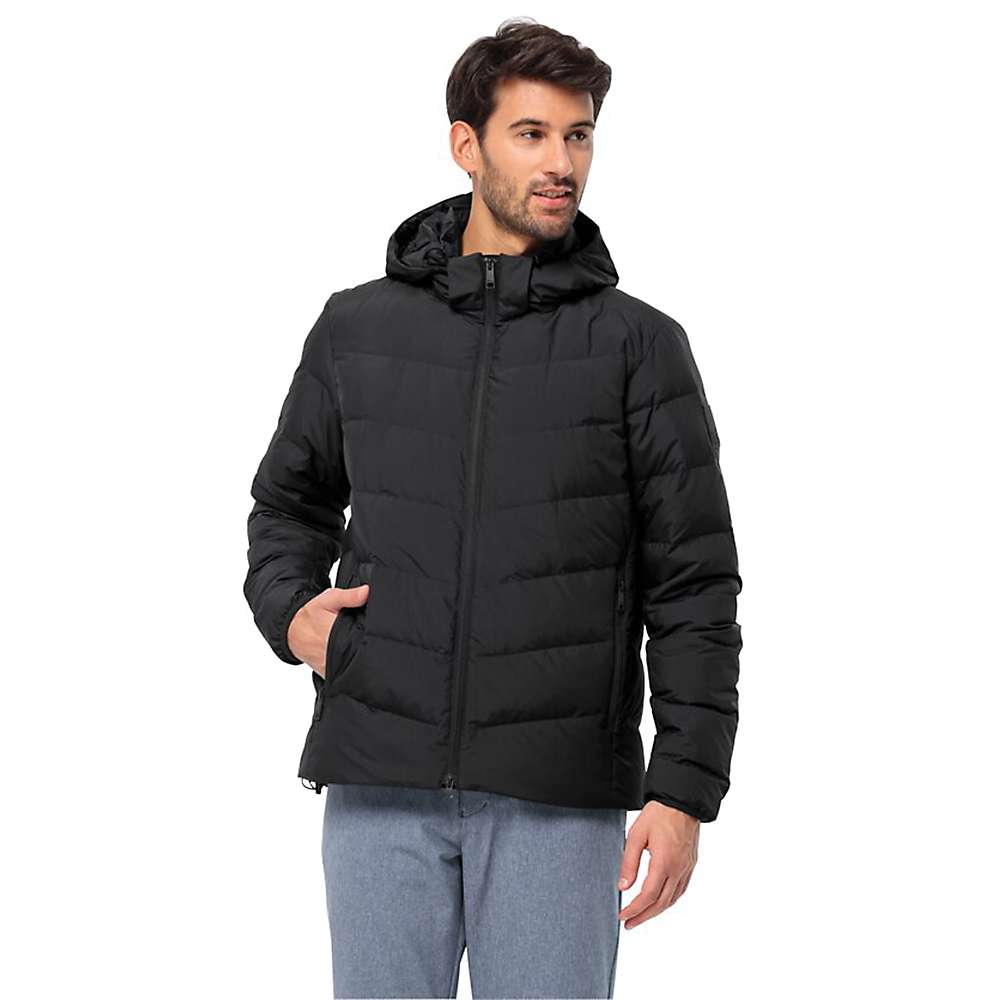 A man wearing a Jack Wolfskin Mens Colonius Jacket in black, with his left hand in the pocket, stands in light gray pants looking to his right against a plain white background.