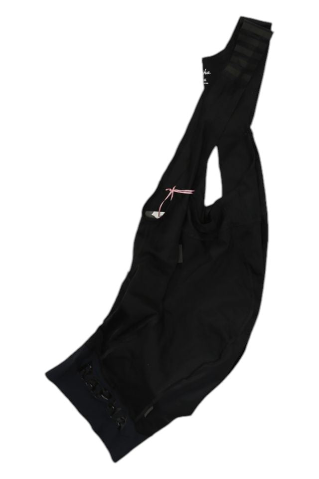 A pair of black Rapha Mens Pro Team Bib Shorts II - Regular with mesh straps, visible Rapha branding near the leg hem, a pink tag attached, and race-grade chamois for comfort.