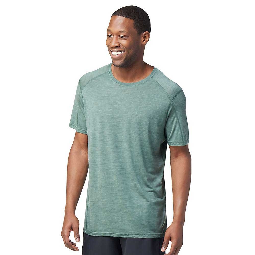 A man is standing and smiling, wearing the Smartwool Men's Merino Sport 120 Mountain Biking SS Tee and dark pants against a plain white background.