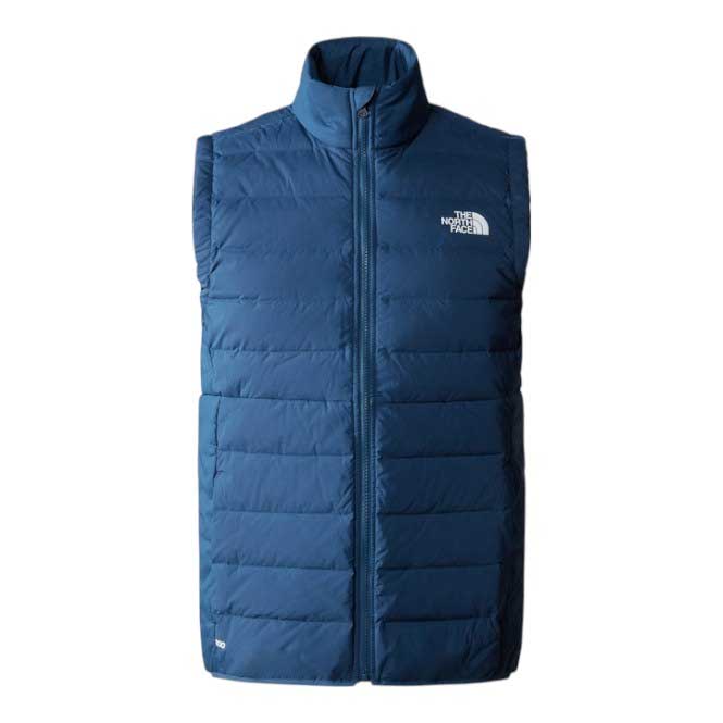 The North Face Women’s Belleview Stretch Down Vest is a blue, slim-fit layer with a front zipper, high collar, and white logo on the left chest. It features horizontal quilting, two side pockets, and is packable for easy adventures.