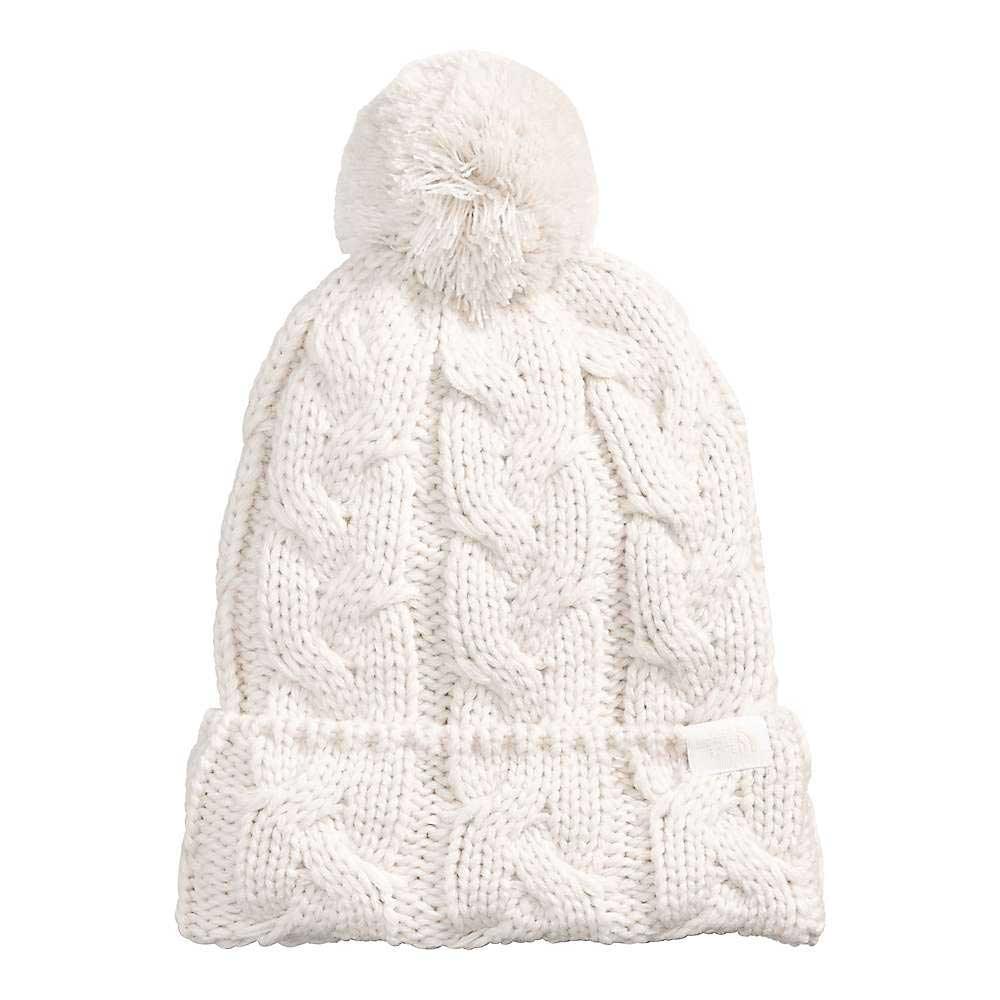 The North Face Cable Minna Pom Beanie is a white, chunky knit beanie with a folded brim and large pom-pom, featuring classic cable pattern and soft recycled fleece lining for warmth.