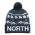 The North Face Ski Tuke is a blue knit beanie with a pom-pom, white mountain and geometric designs, "NORTH" in bold letters, and a small black logo tag on the cuff.