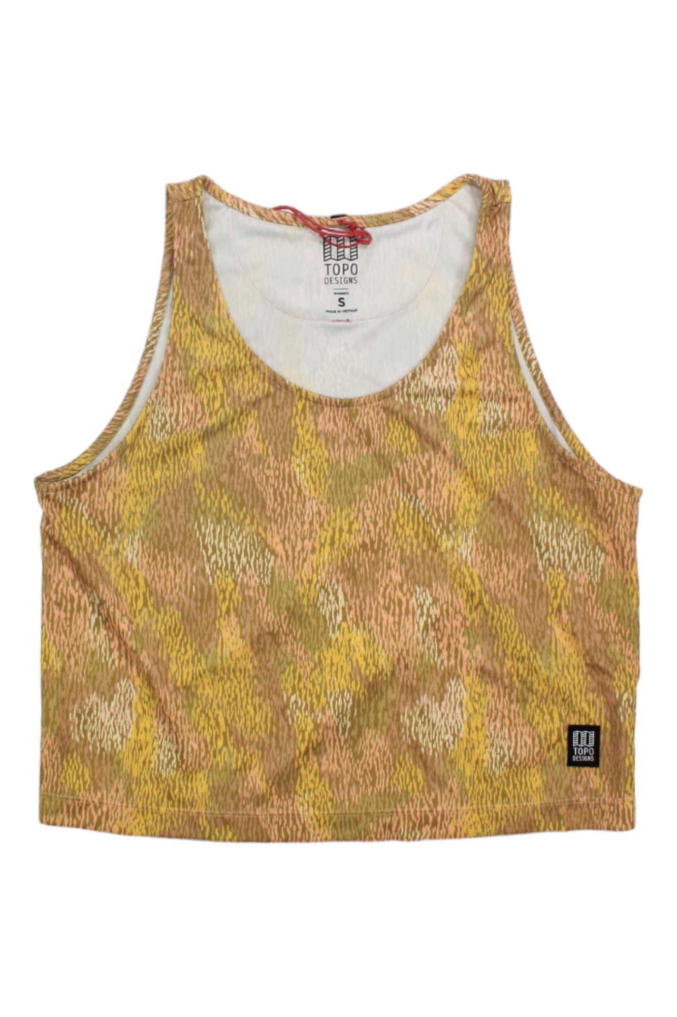 The Topo Designs Womens River Tank is a sleeveless crop top with a round neckline and yellow, brown, and beige abstract pattern. It features a small black patch on the lower front and offers stylish comfort for outdoor adventures.