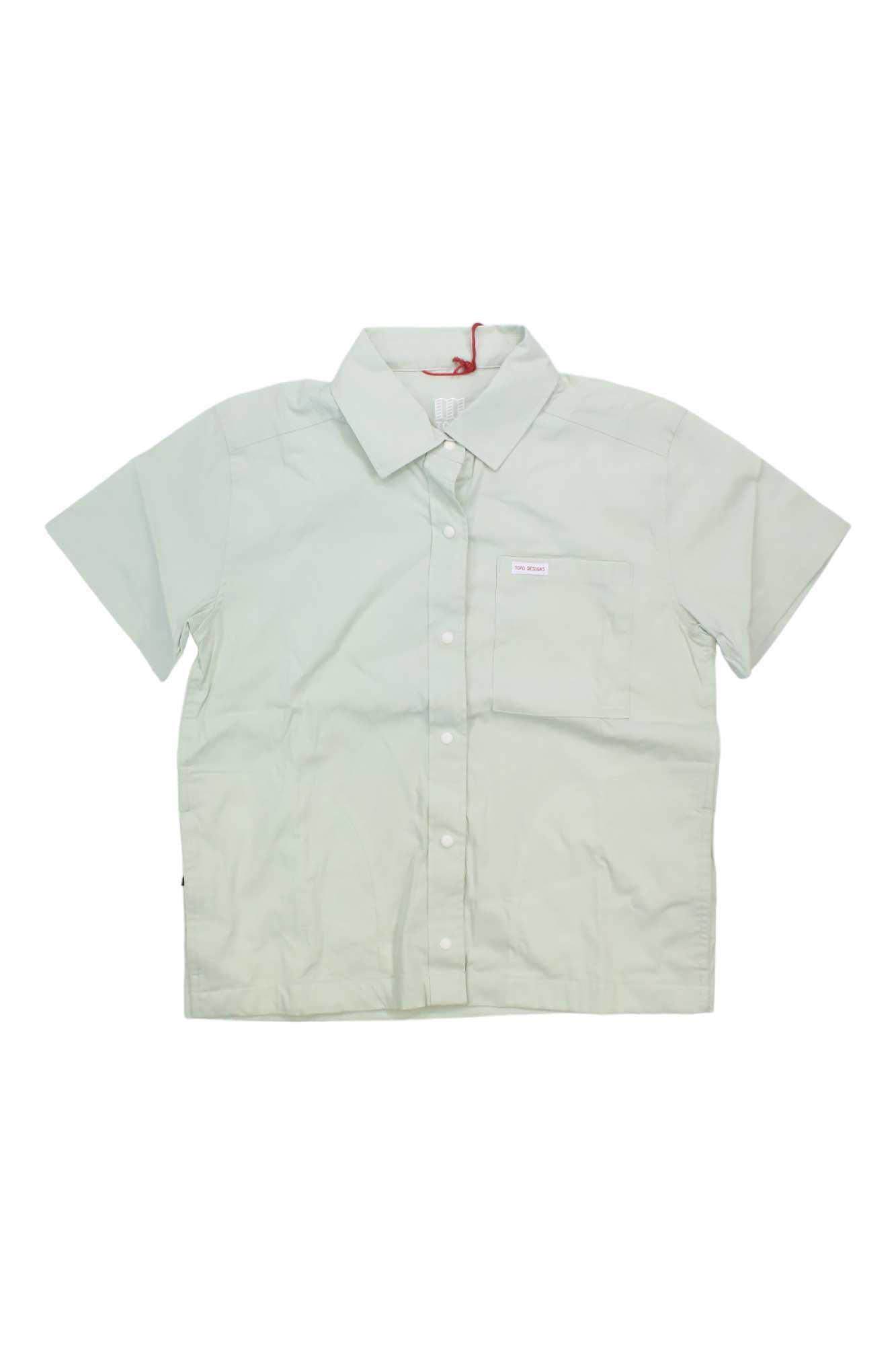 The Topo Designs Women's Global SS Shirt is a light green, short sleeve travel shirt with a collar and left chest pocket. Sun protective and displayed flat on a white background.