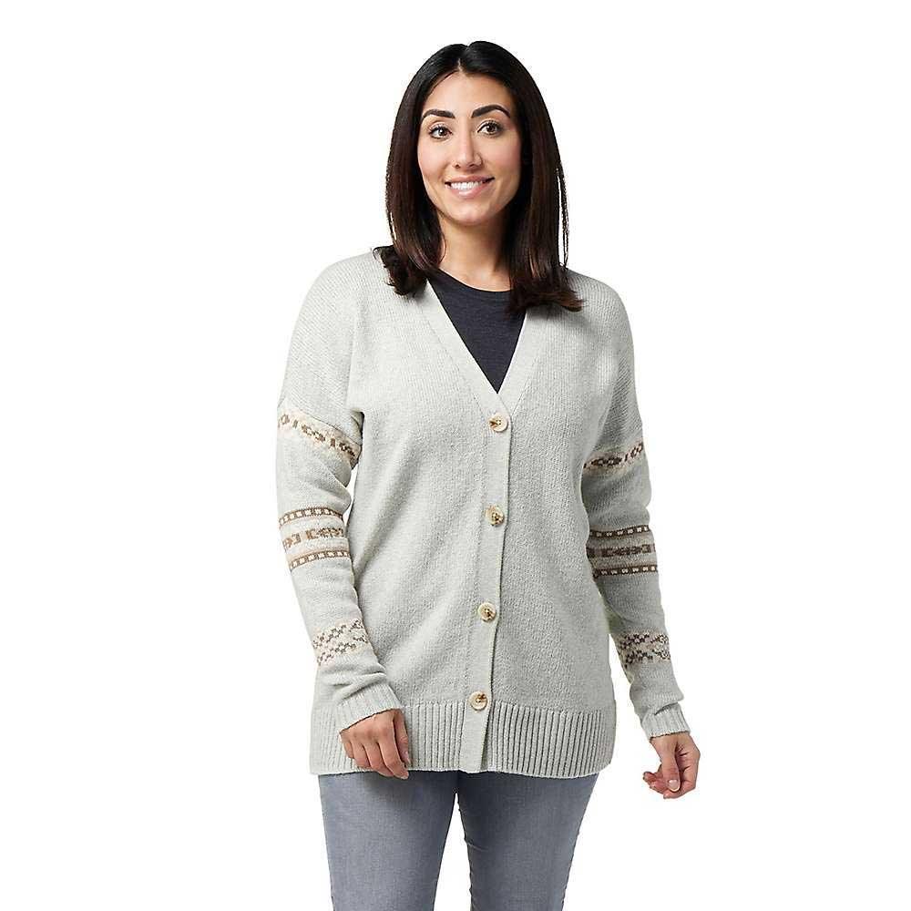 A woman with dark hair smiles in the Smartwool Women's Cozy Lodge Boyfriend Cardigan, featuring patterned striped sleeves, a dark shirt underneath, and gray pants—perfect for a cozy lodge vibe against a white background.