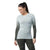 A woman with long dark hair in a ponytail wears the Smartwool Women’s Intraknit Thermal Merino Base Layer Pattern Crew with black and gray sleeves, paired with dark leggings, looking down and smiling.