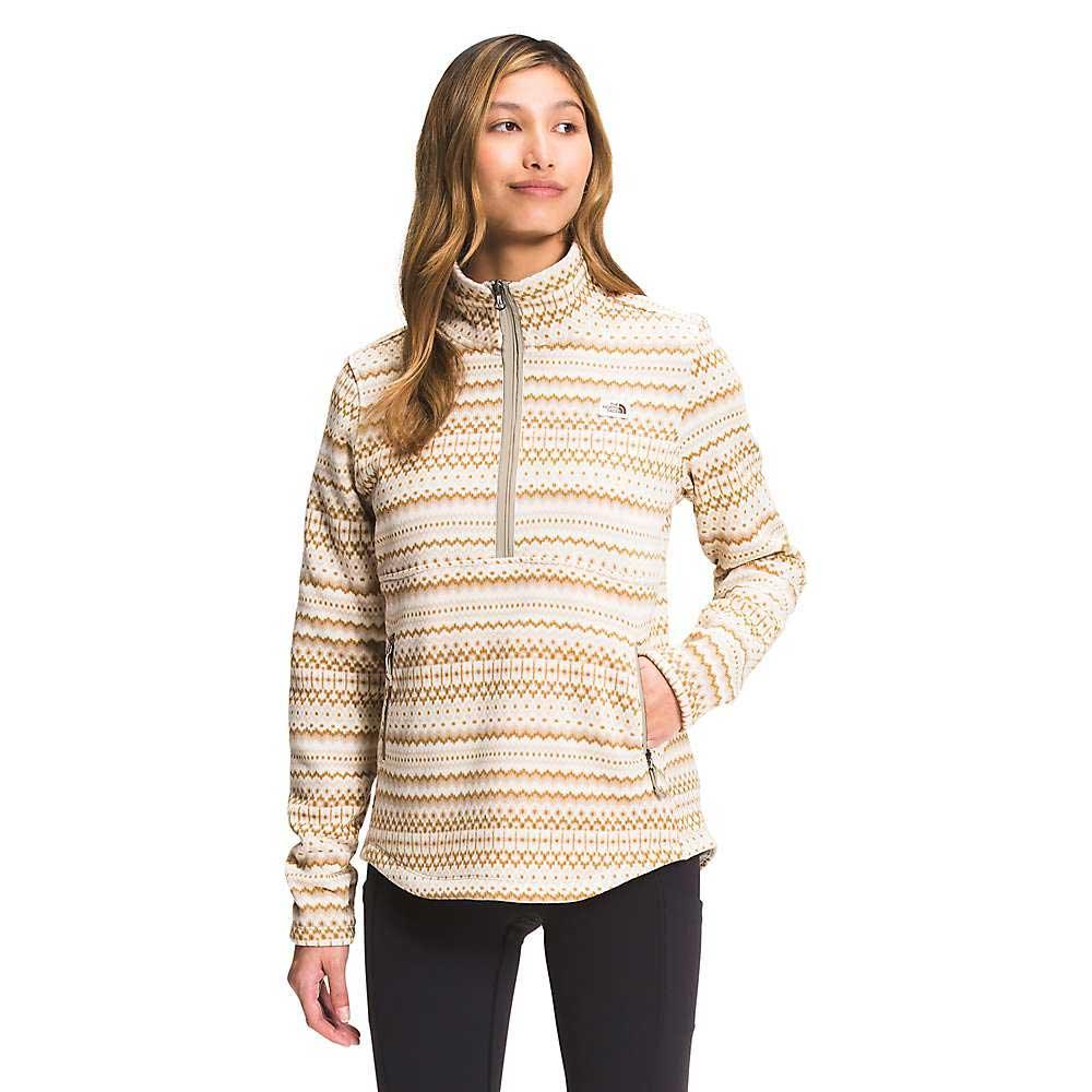 A person stands with one hand in a pocket, wearing The North Face Womens Printed Crescent 1/4 Zip Pullover in cream and tan, high collar visible, gazing slightly to the side.