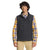 A man stands facing forward against a plain white background, wearing The North Face Mens Camden Soft Shell Vest in dark gray over a yellow plaid shirt and beige pants.