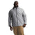 A man wears The North Face Men's Big Alta Vista Jacket—a light gray recycled nylon, waterproof zip-up with hood and logo on the chest—paired with tan pants, standing against a white background.