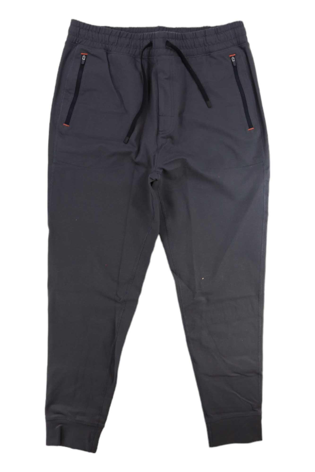 The SAXX Mens Trailzer Jogger, made from dark gray recycled polyester, features an elastic waistband, drawstring, and two zippered side pockets, shown laid flat on a white background.