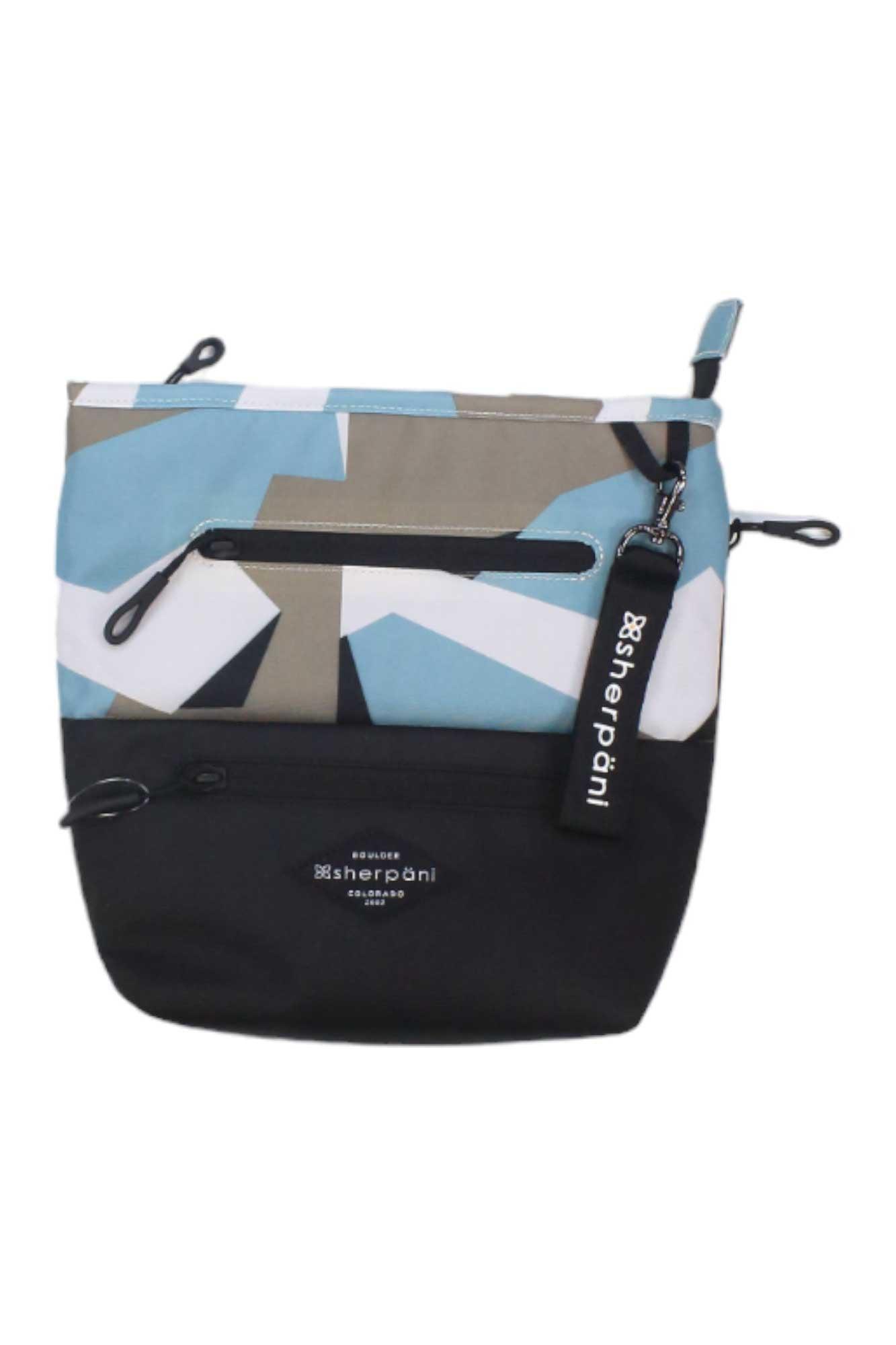The Sherpani Women's Sadie Cross Body Bag features an abstract blue, white, and tan geometric pattern, a solid black bottom, two zippered pockets, RFID-protected lining, and a branded keychain.