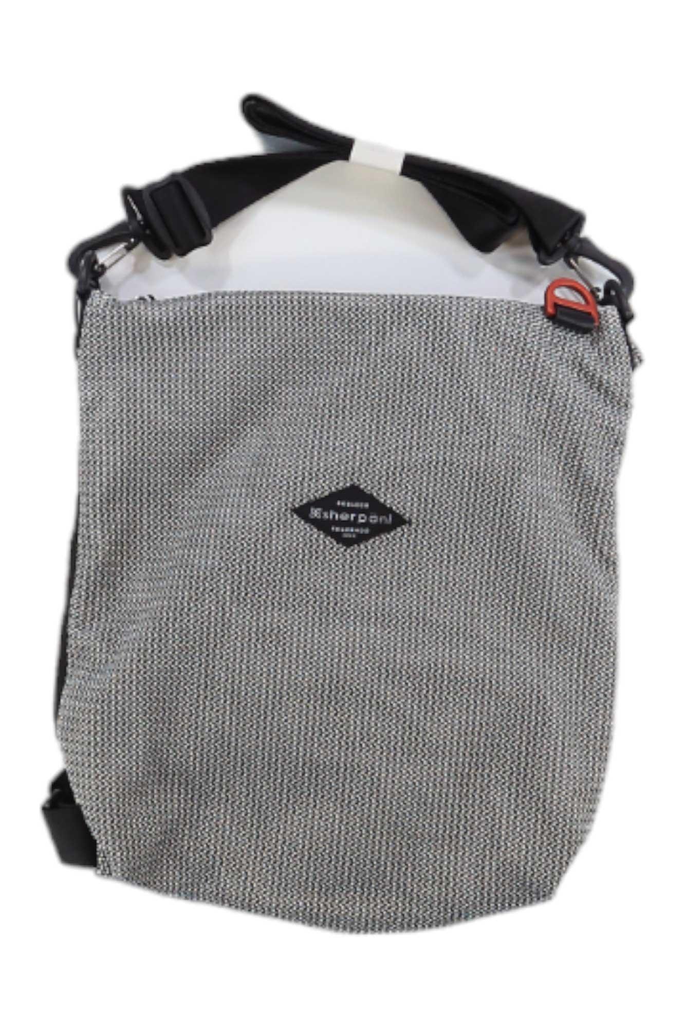 The Sherpani Delanie Crossbody Bag + Backpack features a gray textured design, black adjustable strap, small front logo patch, orange clip near the top, and water-resistant material for stylish durability.