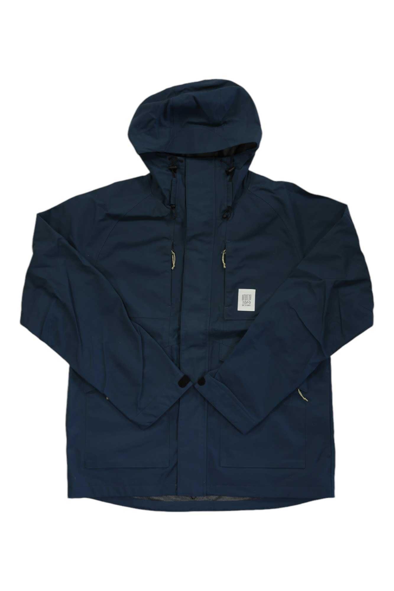The Topo Designs Mens Mountain Parka, in navy blue, features a front zipper, hood drawstrings, two large front pockets, and a small square white label on the left chest. The jacket is displayed flat on a white background.