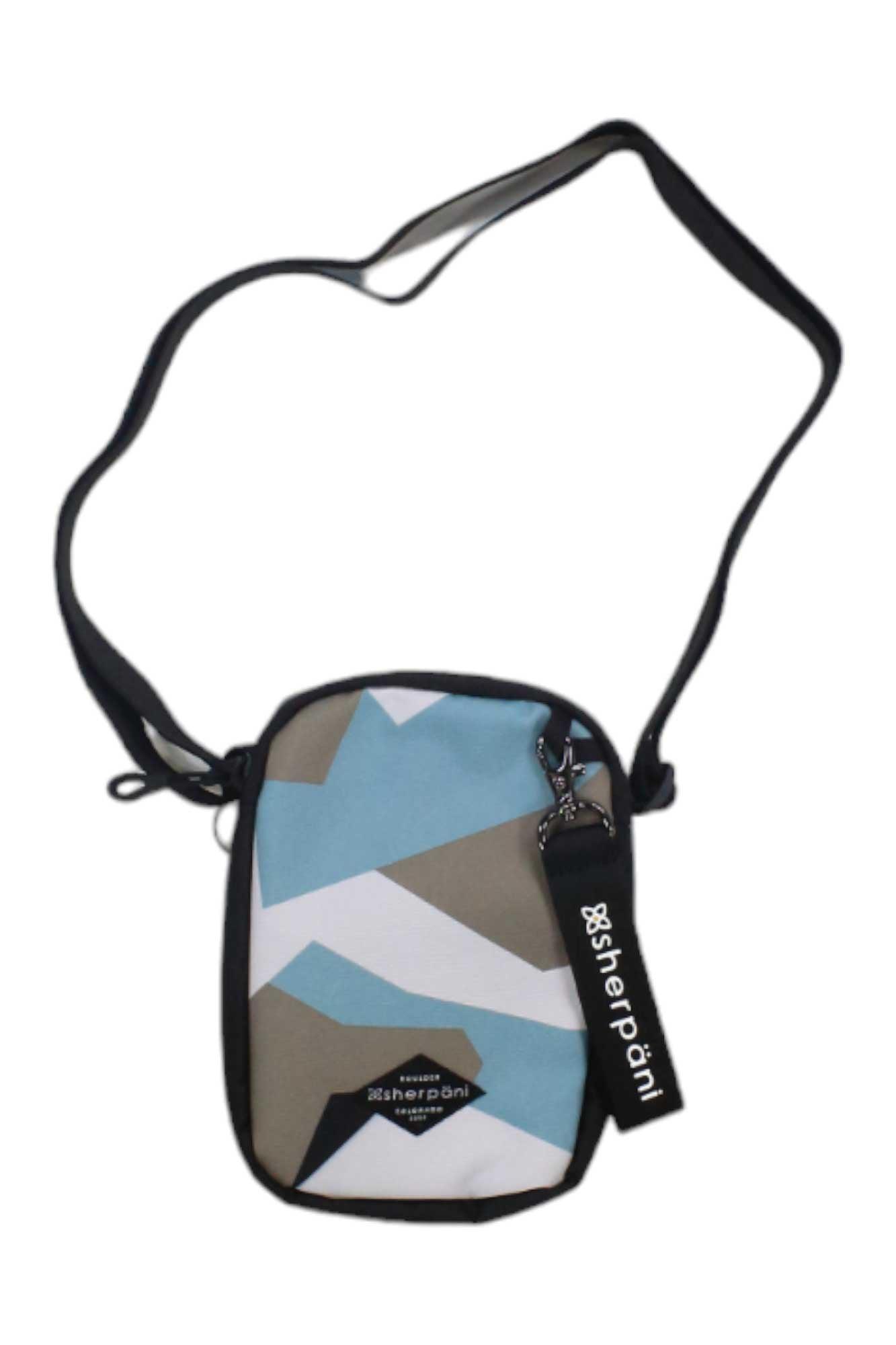 The Sherpani Women's Rogue Mini Crossbody Bag is a small women’s bag with a black strap, made from recycled polyester. It features blue, white, and gray geometric patterns, a black zipper, and a Sherpani tag.