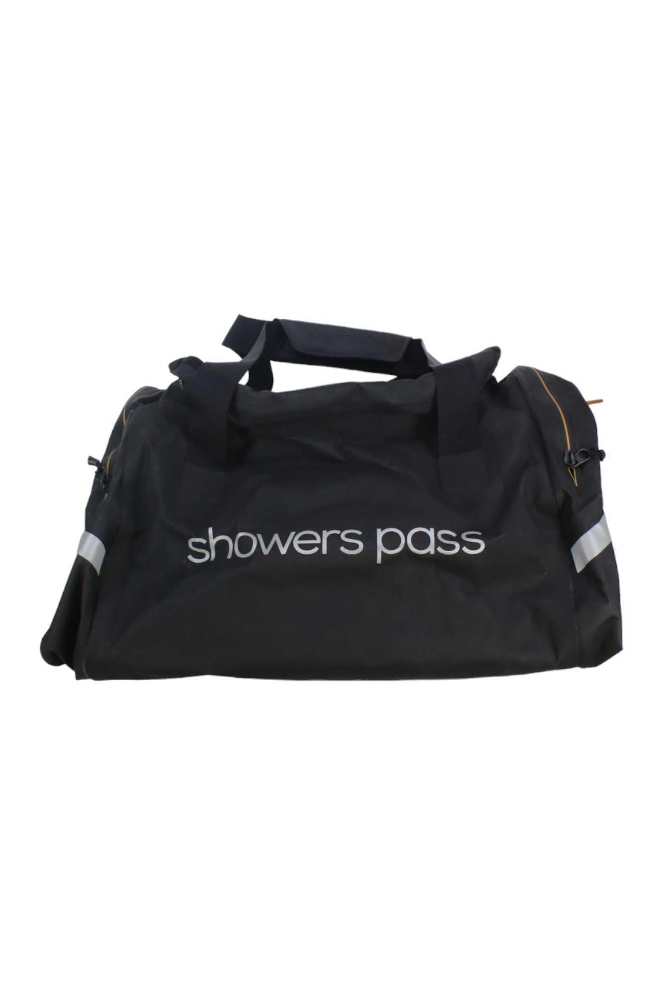 The Showers Pass Waterproof Duffel Bag is crafted from black ballistic nylon with a white logo, features two carrying handles and reflective accents, and is perfect for carrying cycling gear.