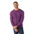 A man wearing a long-sleeved, purple Smartwool Mens Sparwood Crew Sweater and dark jeans stands against a white background, smiling with his hands loosely clasped in front of him.