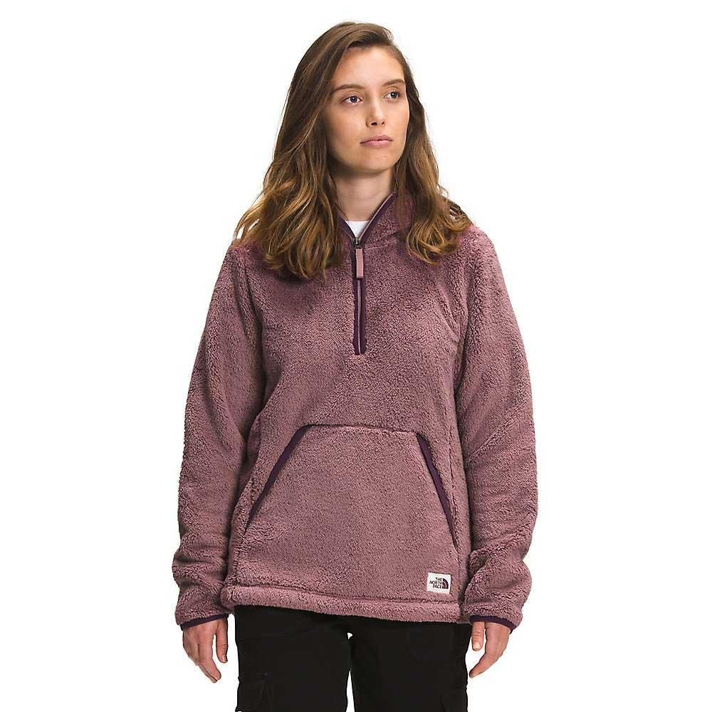 A woman wearing The North Face Women's Campshire Pullover Hoodie 2.0 in mauve, featuring fuzzy Sherpa fleece, a partial zipper, and a front pocket, stands facing forward with a neutral expression against a plain background.
