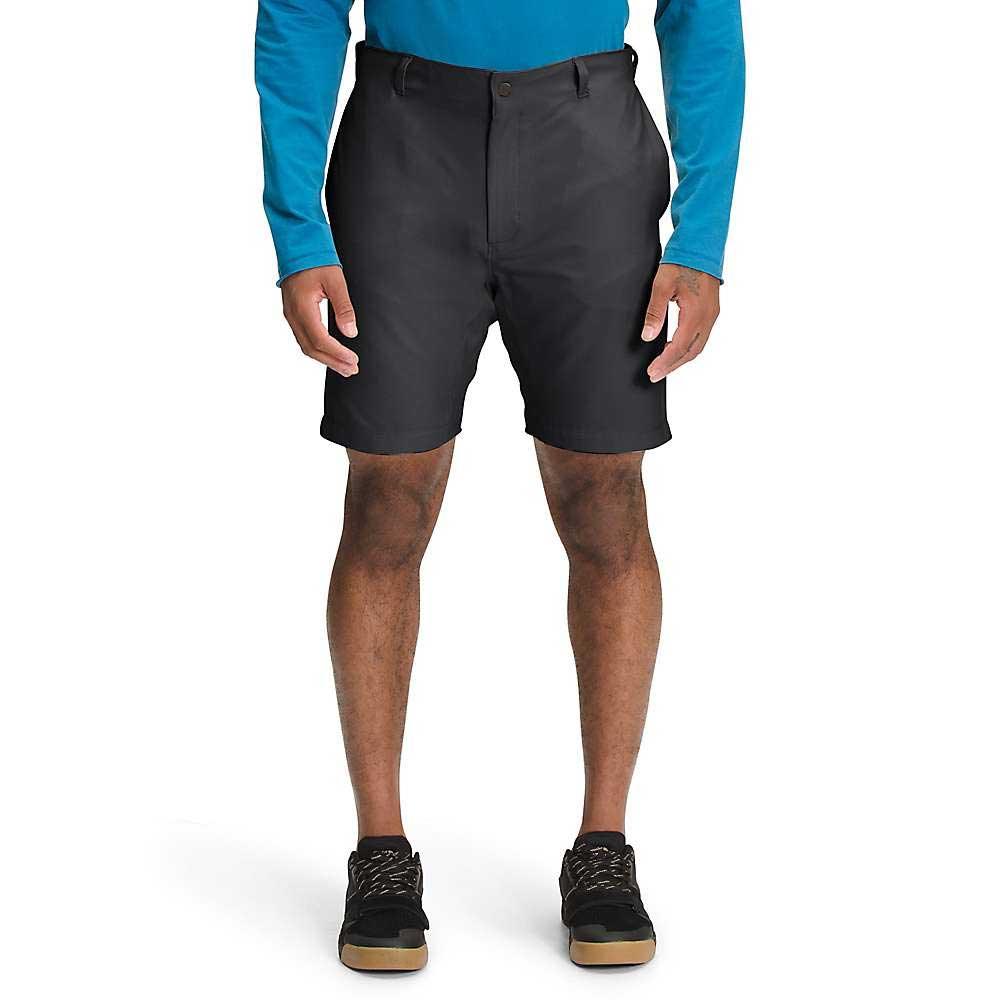 A person wearing a bright blue long-sleeve shirt, The North Face Men's Project 8 Inch Short, and black sneakers stands against a white background, visible from shoulders to feet.