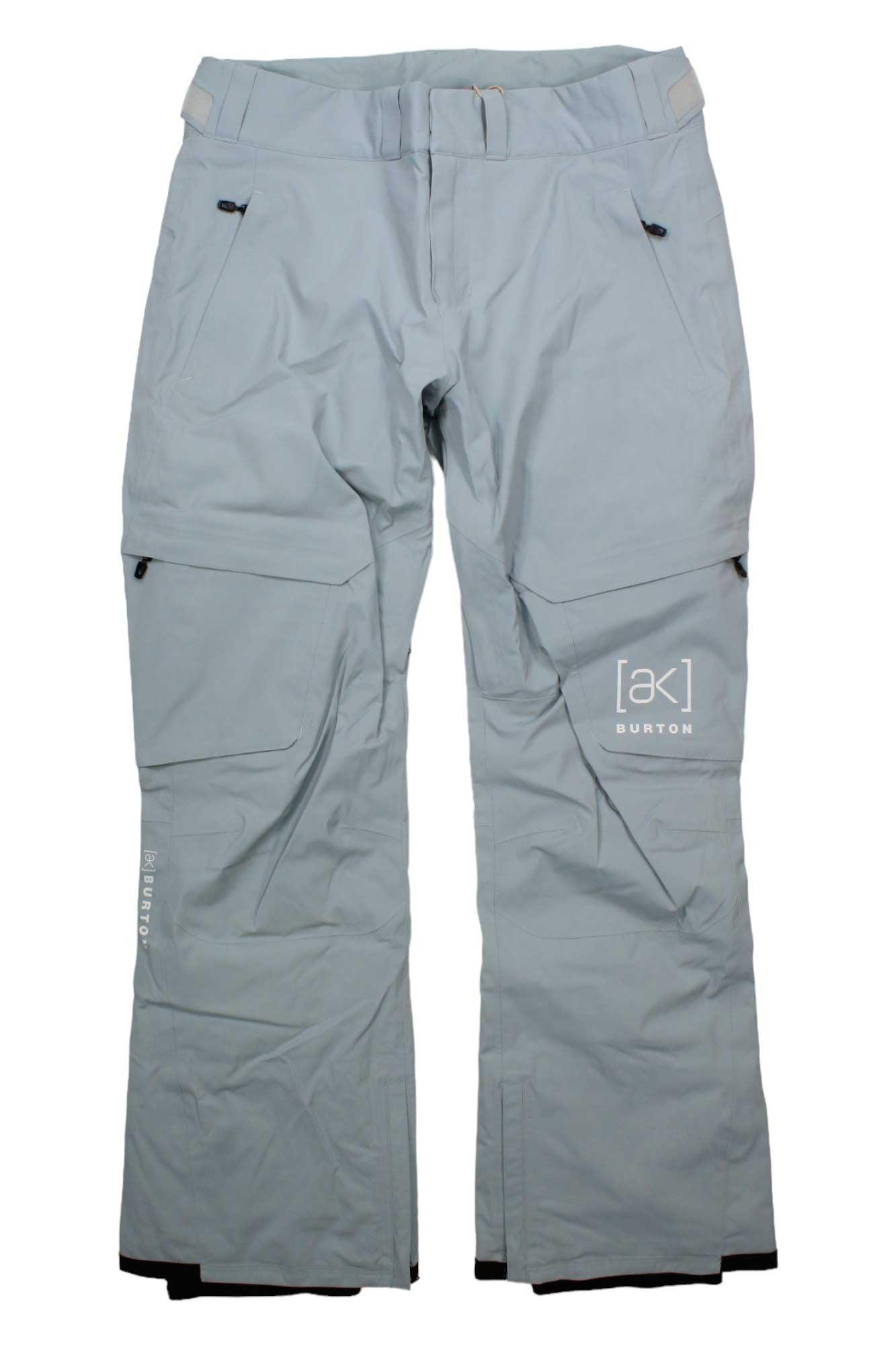 Light gray Burton Womens [ak] GTX Summit Insulated Pant laid flat, featuring zippered pockets, articulated knees, belt loops, reinforced ankle cuffs, and Burton branding on the left thigh and right leg.