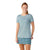 A woman with long reddish hair in a ponytail wears a Smartwool Women’s Merino Sport 150 Tee in light blue and a blue plaid skirt, smiling as she stands against a plain white background.