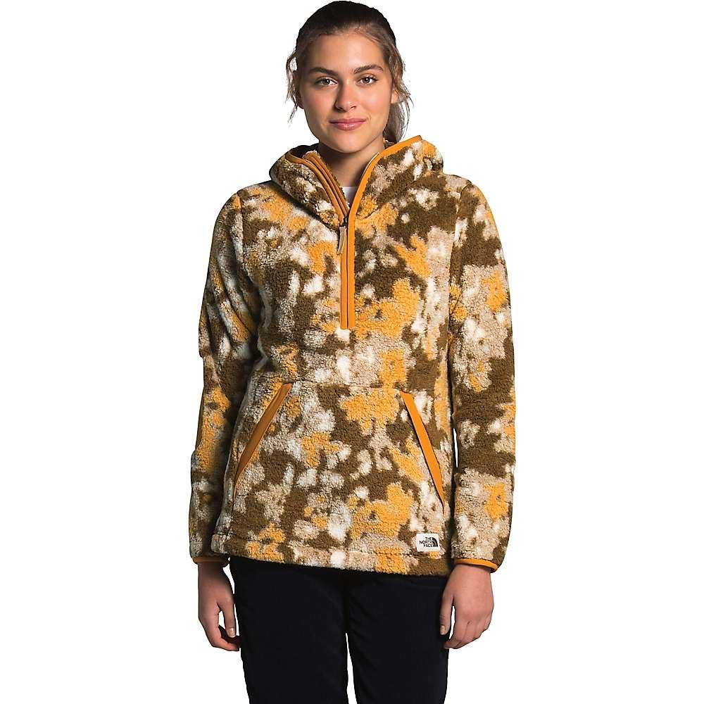 A woman faces forward wearing The North Face Women's Campshire Pullover Hoodie 2.0 in brown, yellow, and white camo with a front zipper. This cozy mountaineering hoodie is shown against a plain white background.